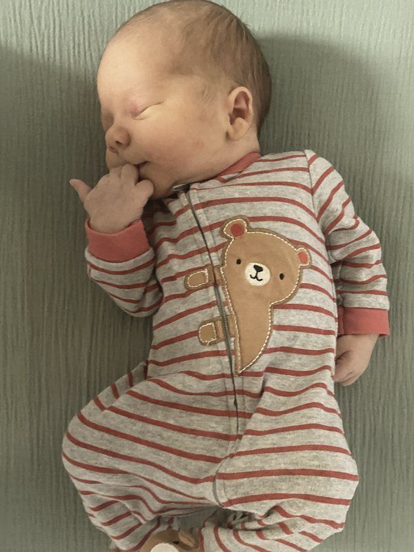 Christian’s newborn son sleeping in a striped teddy bear sleeper
